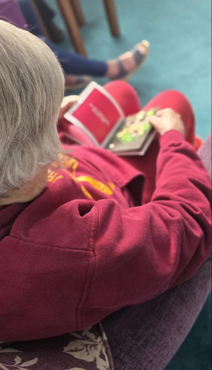 An older woman sat in a chair reading