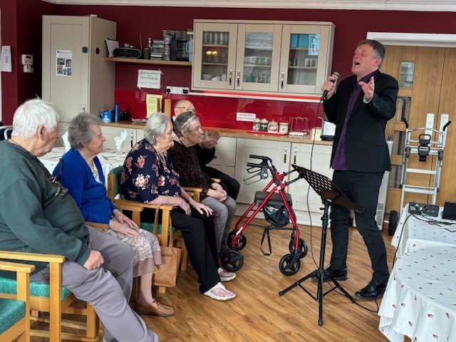 A group of people watching an entertainer sing