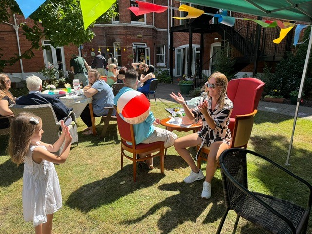 People and children playing ball games at a summer garden party