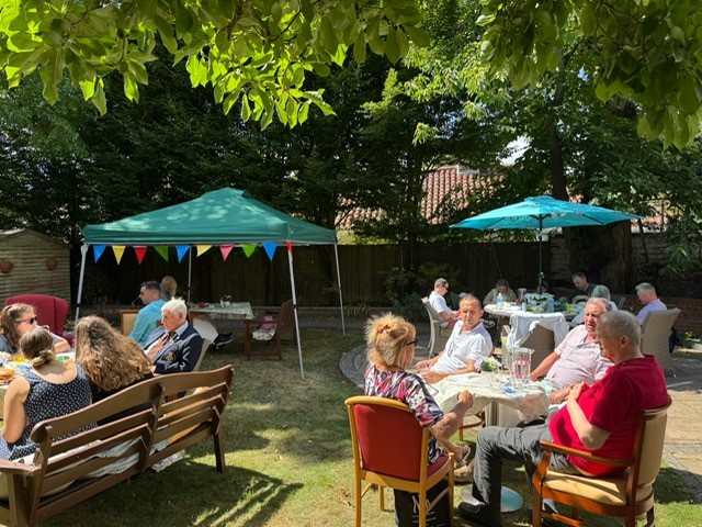 People sitting on garden furniture enjoying refreshments at a summer garden party