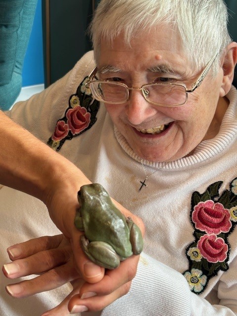 An older woman looking closely at a frog