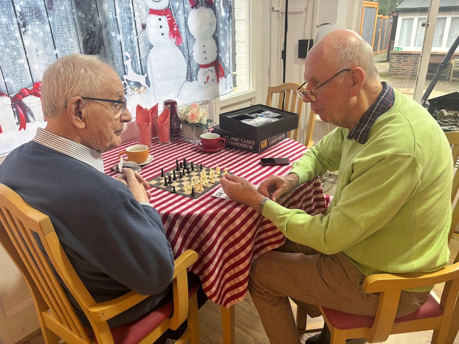 Two older gentleman sat at a table playing chess