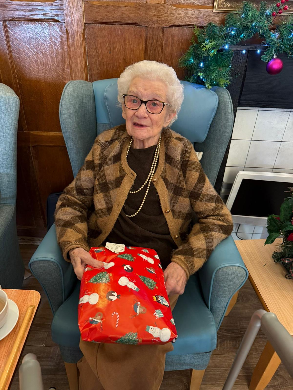 An elderly lady opening a Christmas present