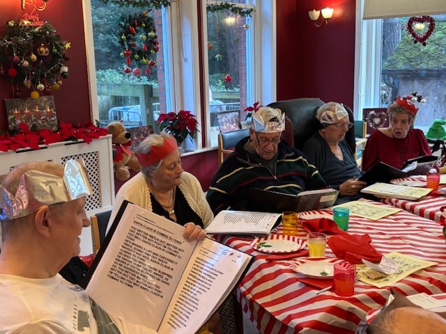 A group of people sat around a table in paper crowns at a Christmas party