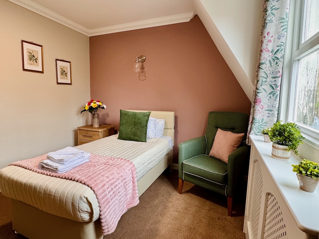 A well presented bedroom with pink and green decor and floral elements