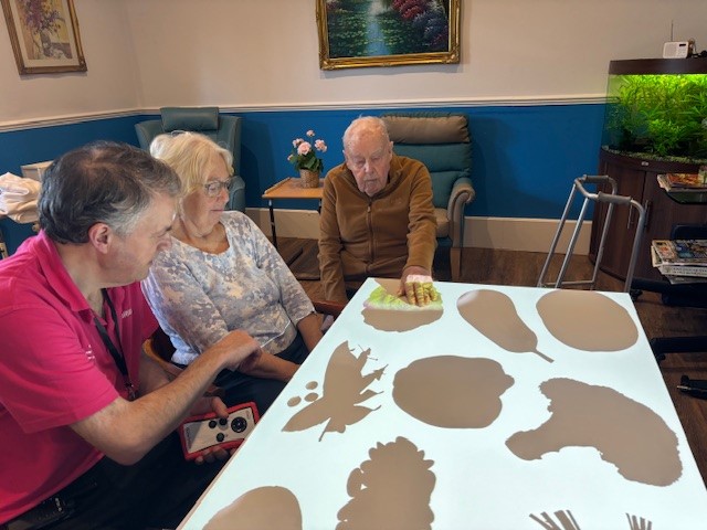 Two residents taking part in an interactive activity with the support of a staff member
