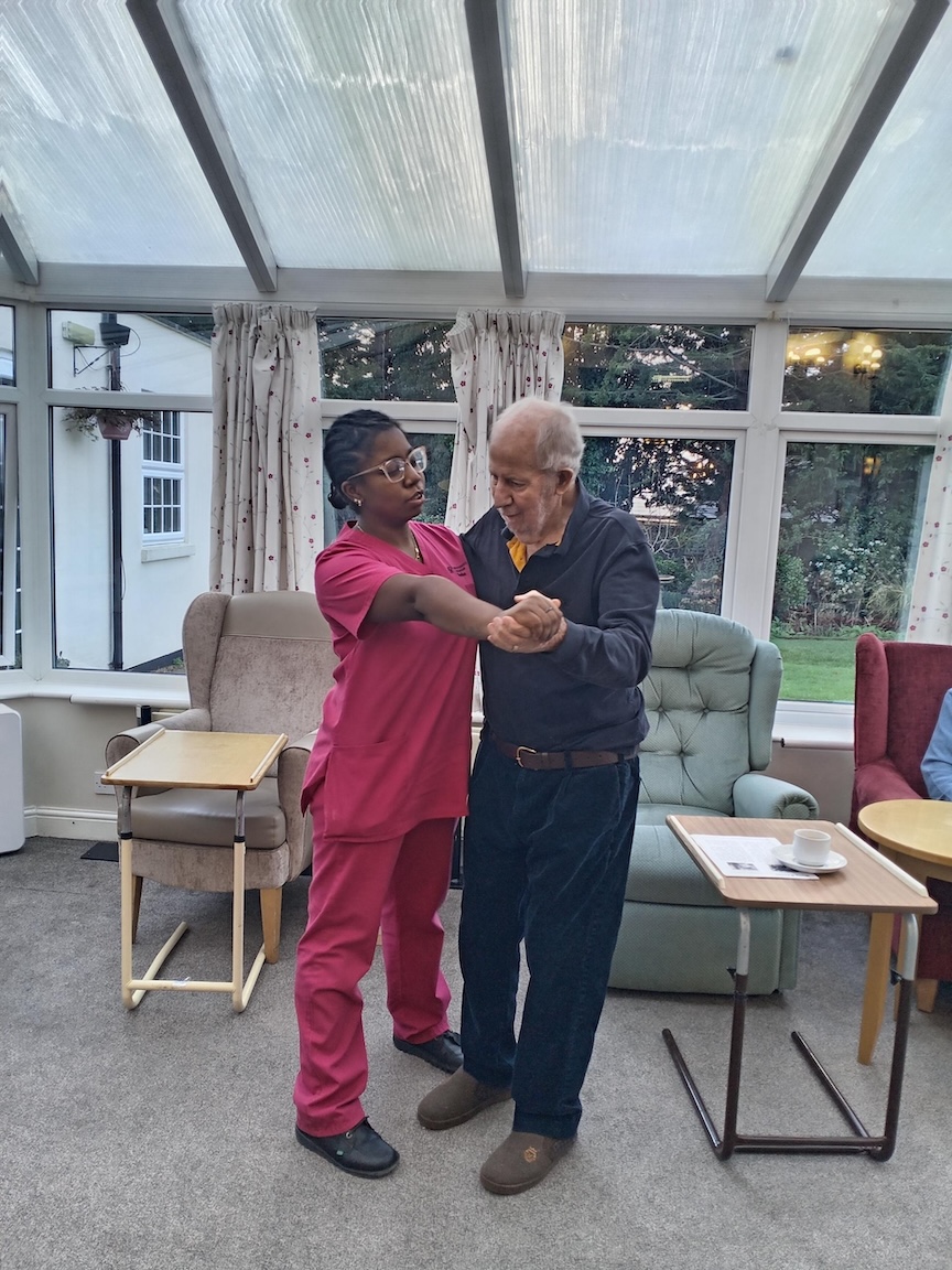 A resident and staff member dancing together