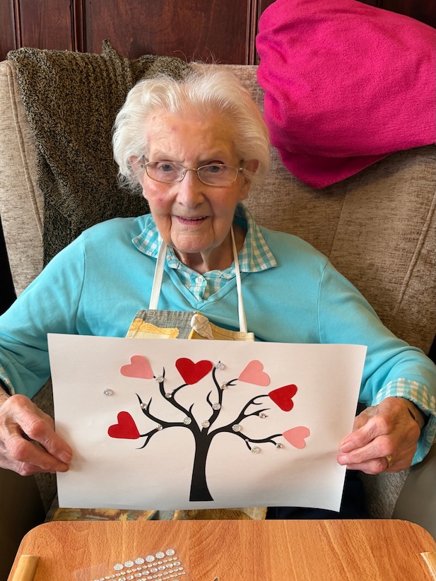 Elderly lady smiling holding up a picture