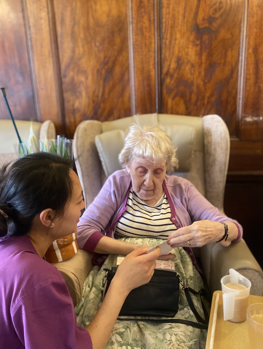 An older woman opening a birthday card with the help of a staff member