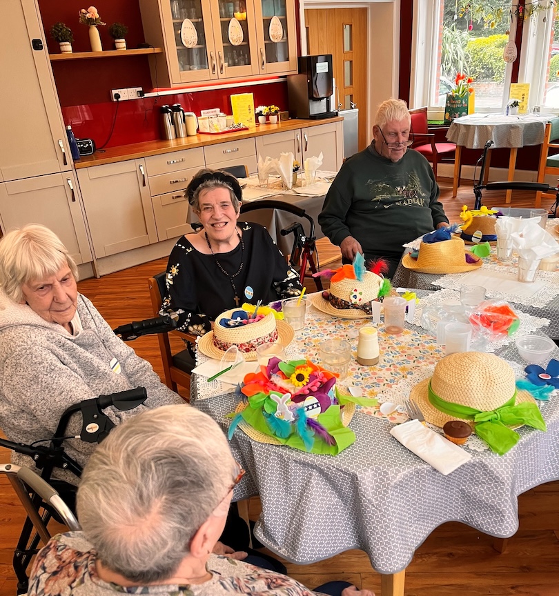 A group of people sat around a table doing arts and crafts activities