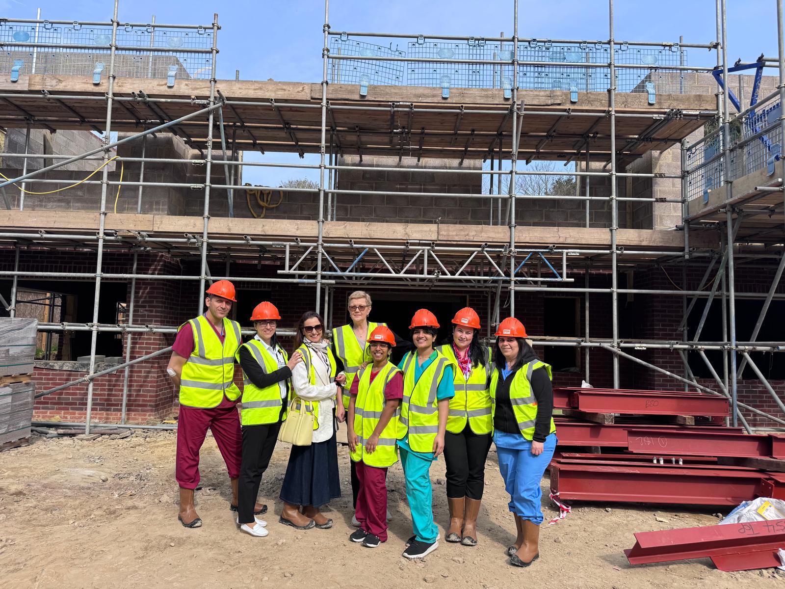 A group of people in hard hats and high-vis vests stood in front of a construction site