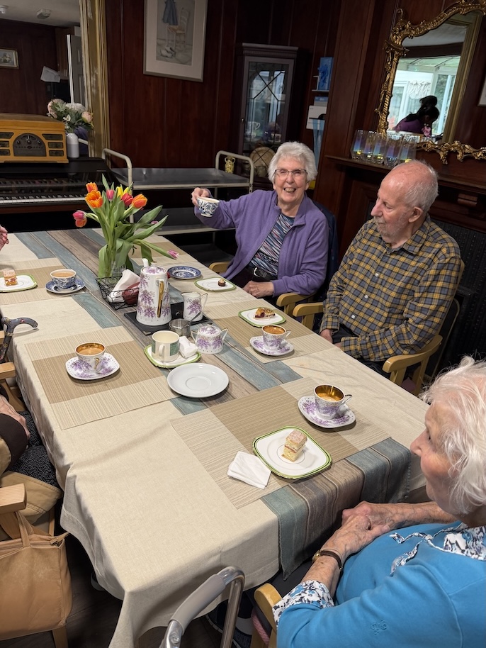 A group of people sat around a table drinking tea