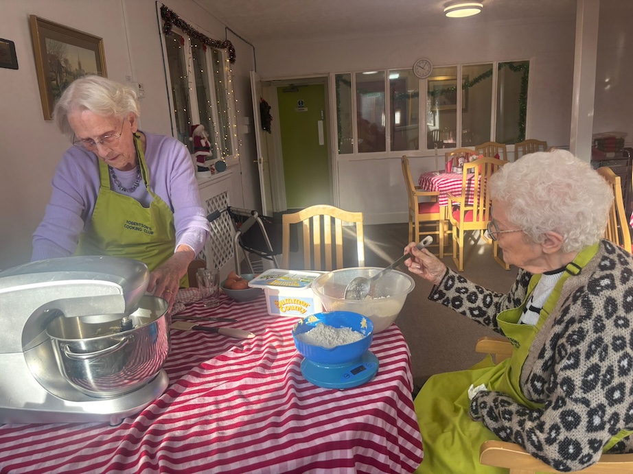 Two ladies mixing ingredients to make a cake