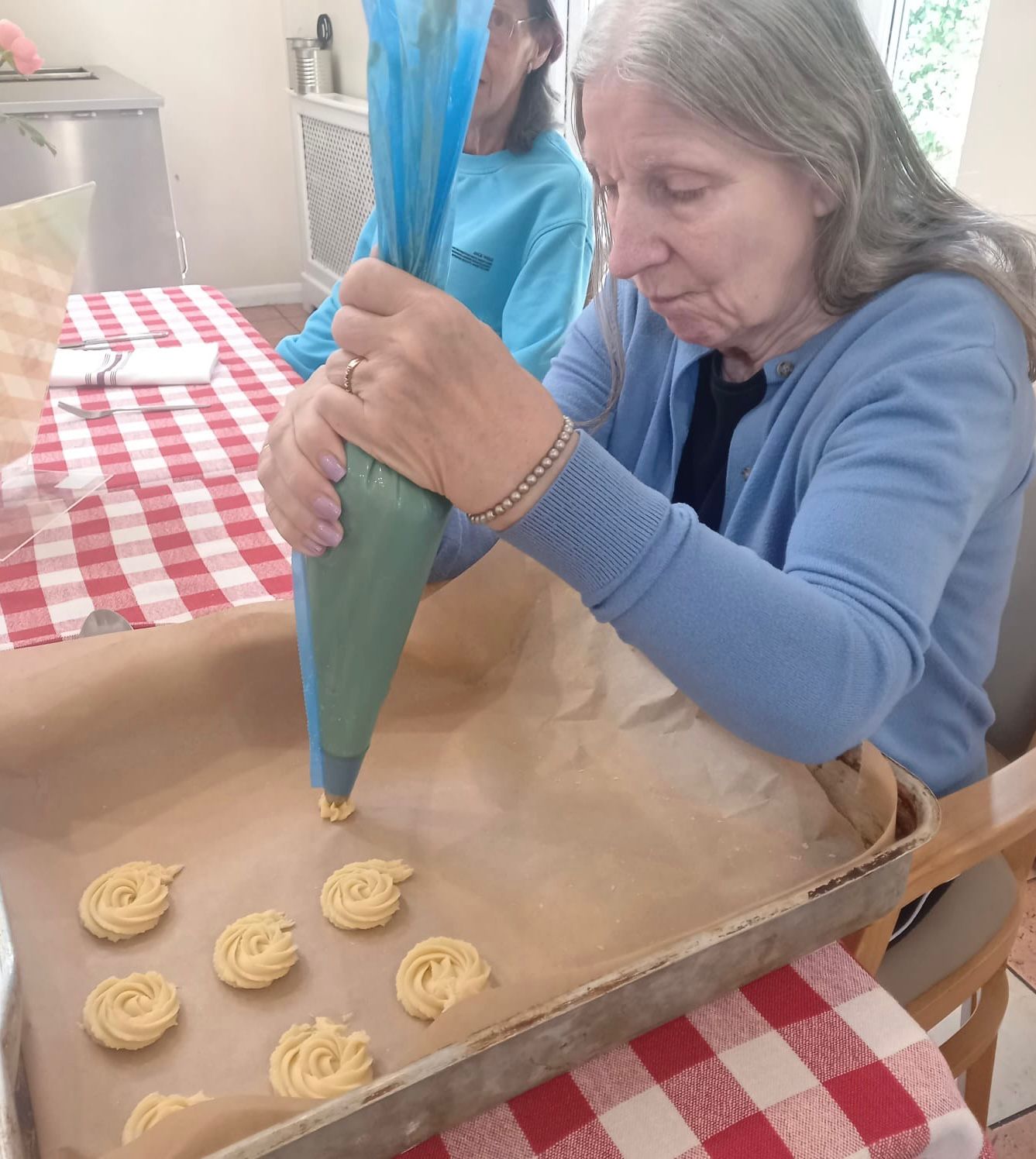 A woman piping biscuit dough onto a baking tray