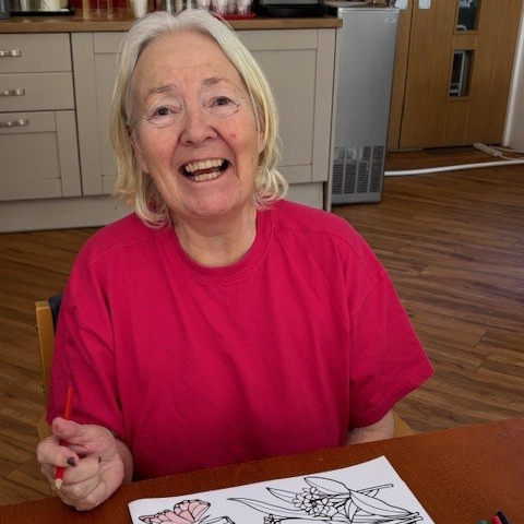 A woman smiling while colouring in a picture
