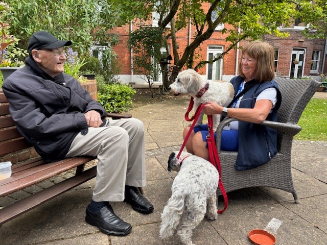 A man and woman sat in a garden with two dogs