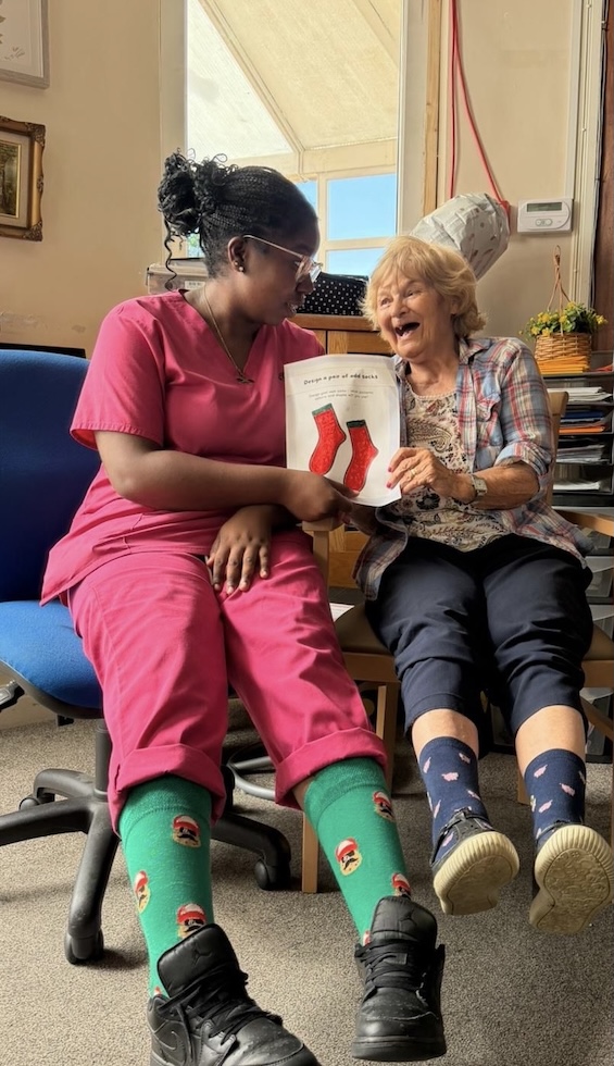 A staff member and resident smiling wearing colourful socks