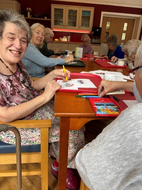 A group of people sat around a table doing arts and crafts activities