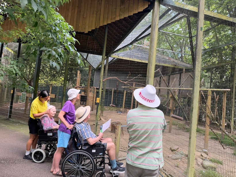 A group of people stood looking at an aviary