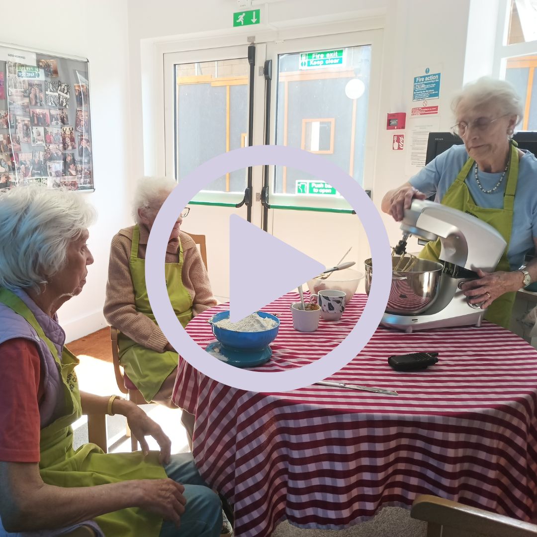 Three women sat around a table baking a cake