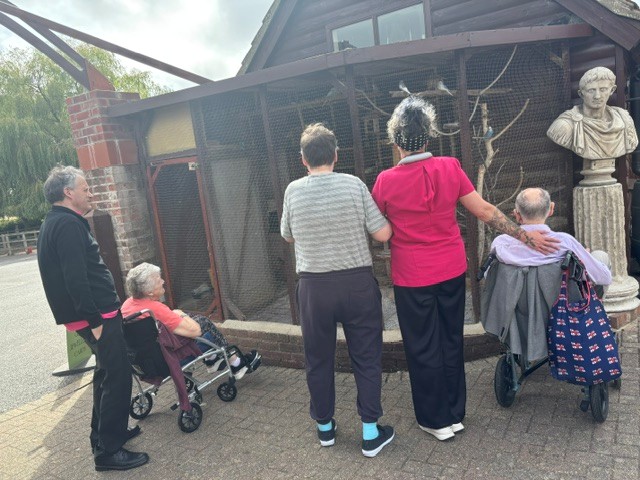 A group of people stood looking at an aviary