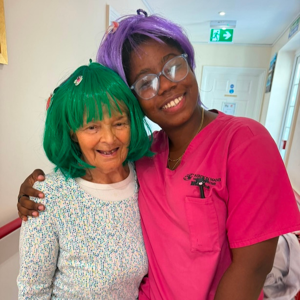 Two people smiling in colourful wigs