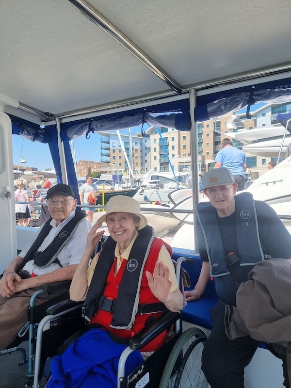 A group of older people smiling wearing life jackets on a boat