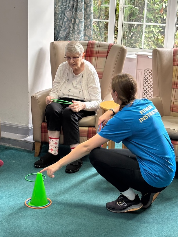 A staff member helping an older woman with an exercise game