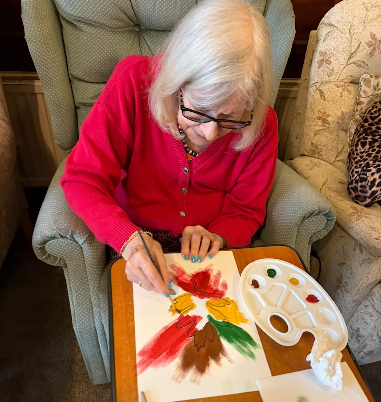 An older woman sat painting