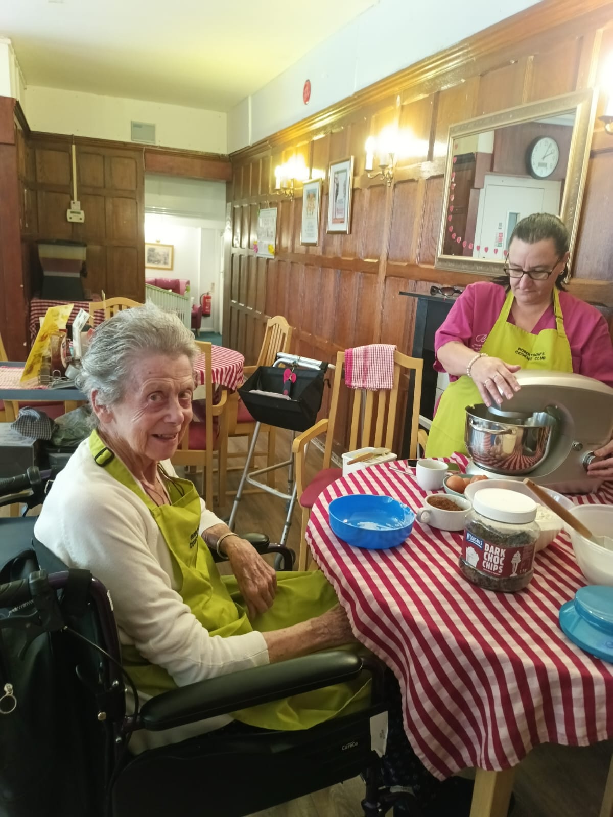A woman and staff member at a table baking a cake
