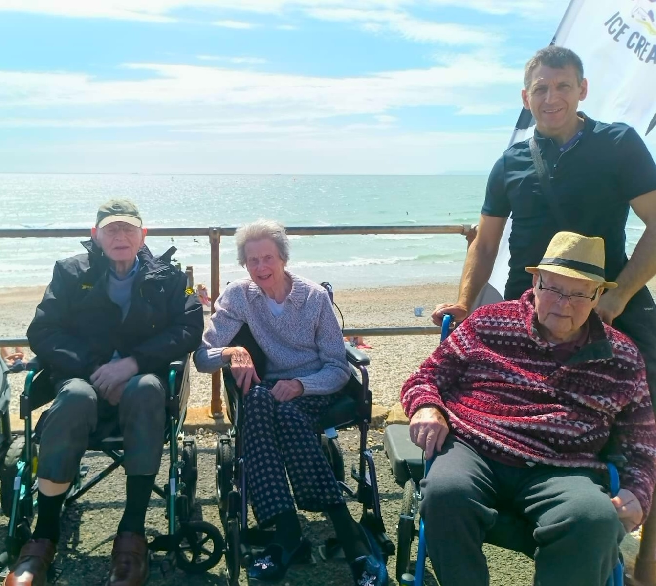 A group of people stood smiling in front of the beach