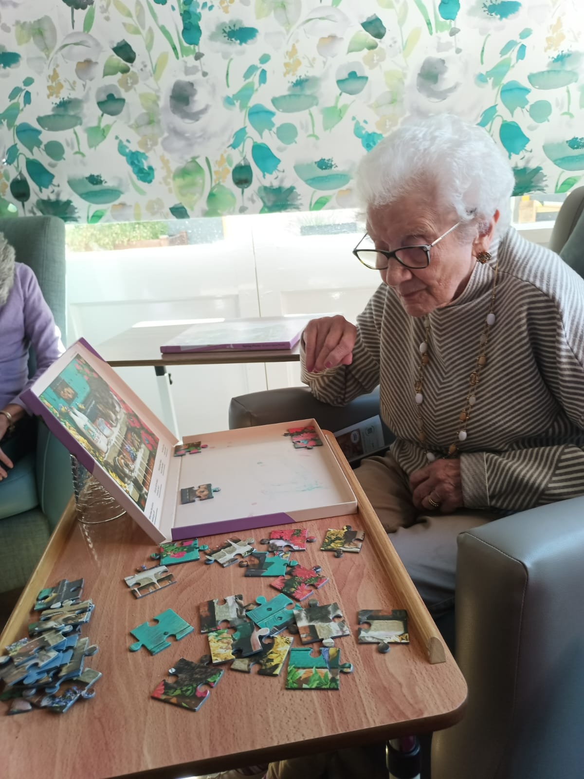 An older woman doing a puzzle