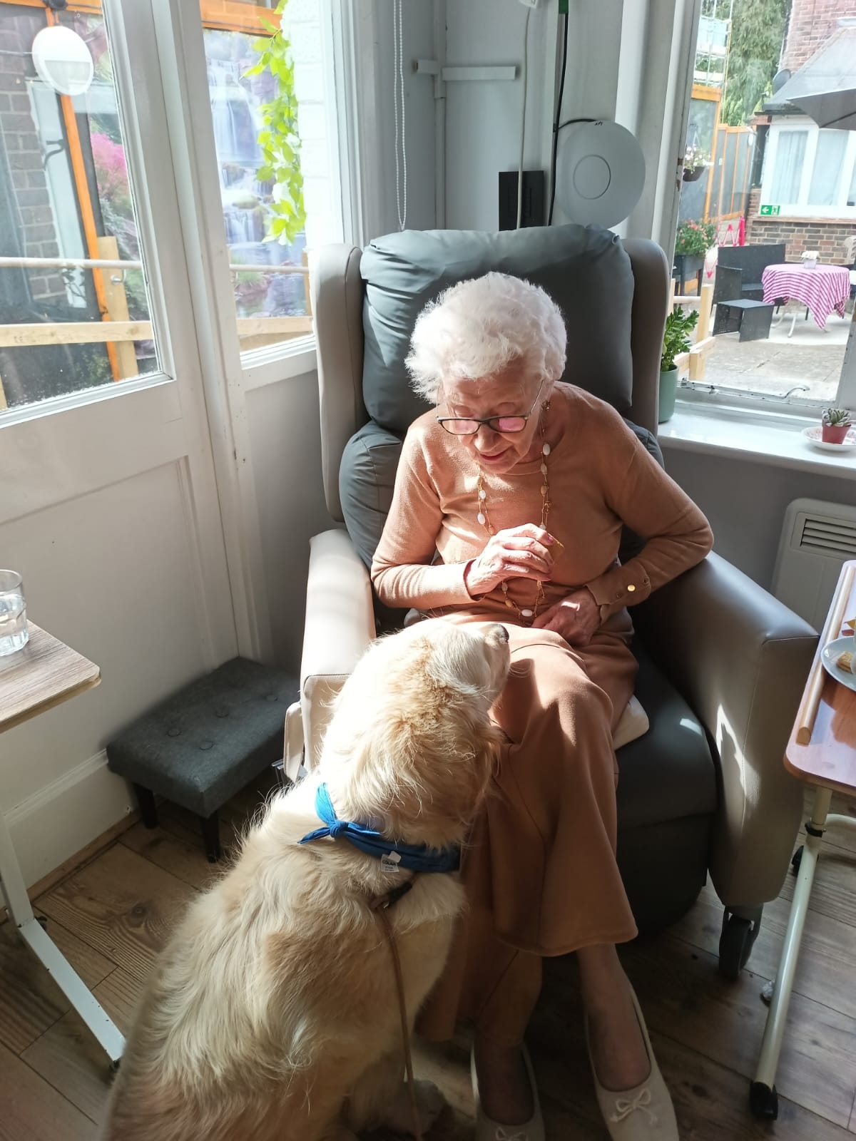 A woman sat in a chair with a dog sat at her feet