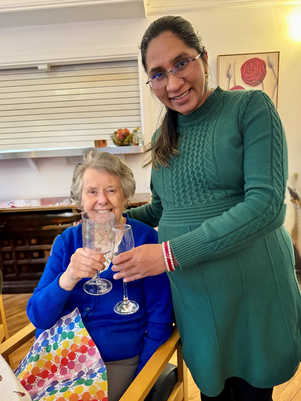 A smiling preganant woman next to a happy elderly lady.