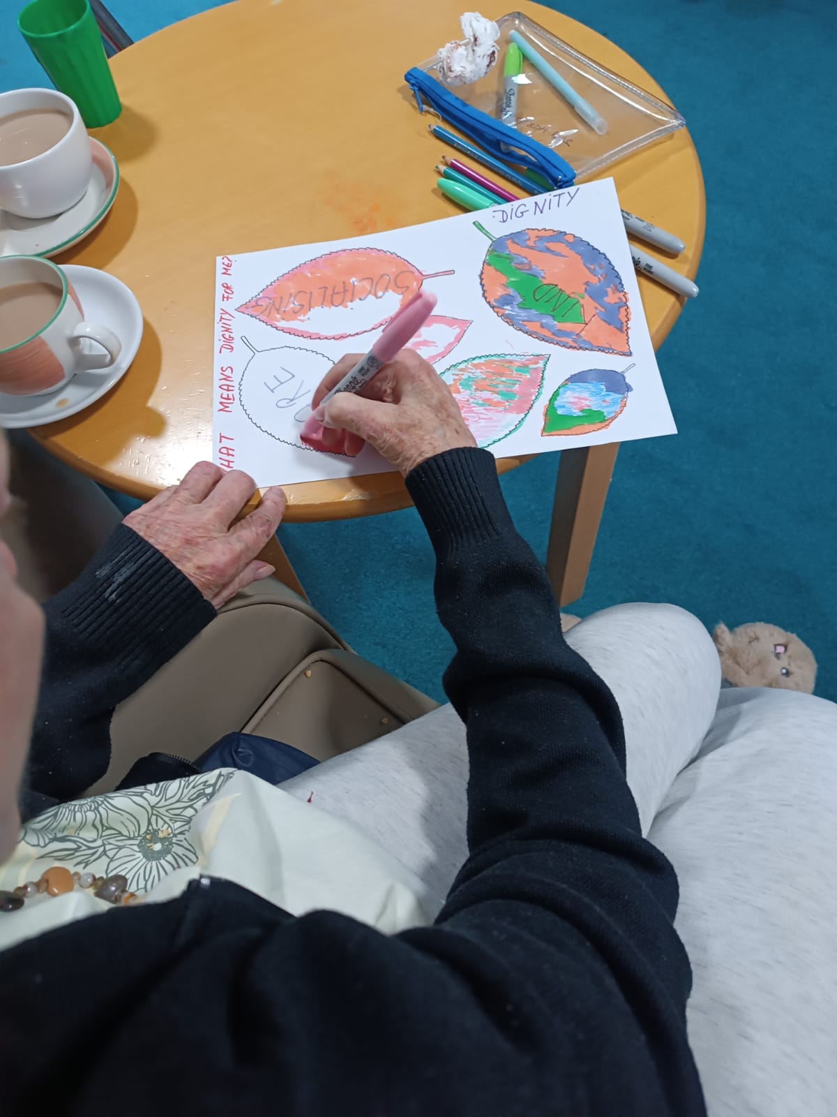 An elderly woman drawing a leaf on a piece of paper
