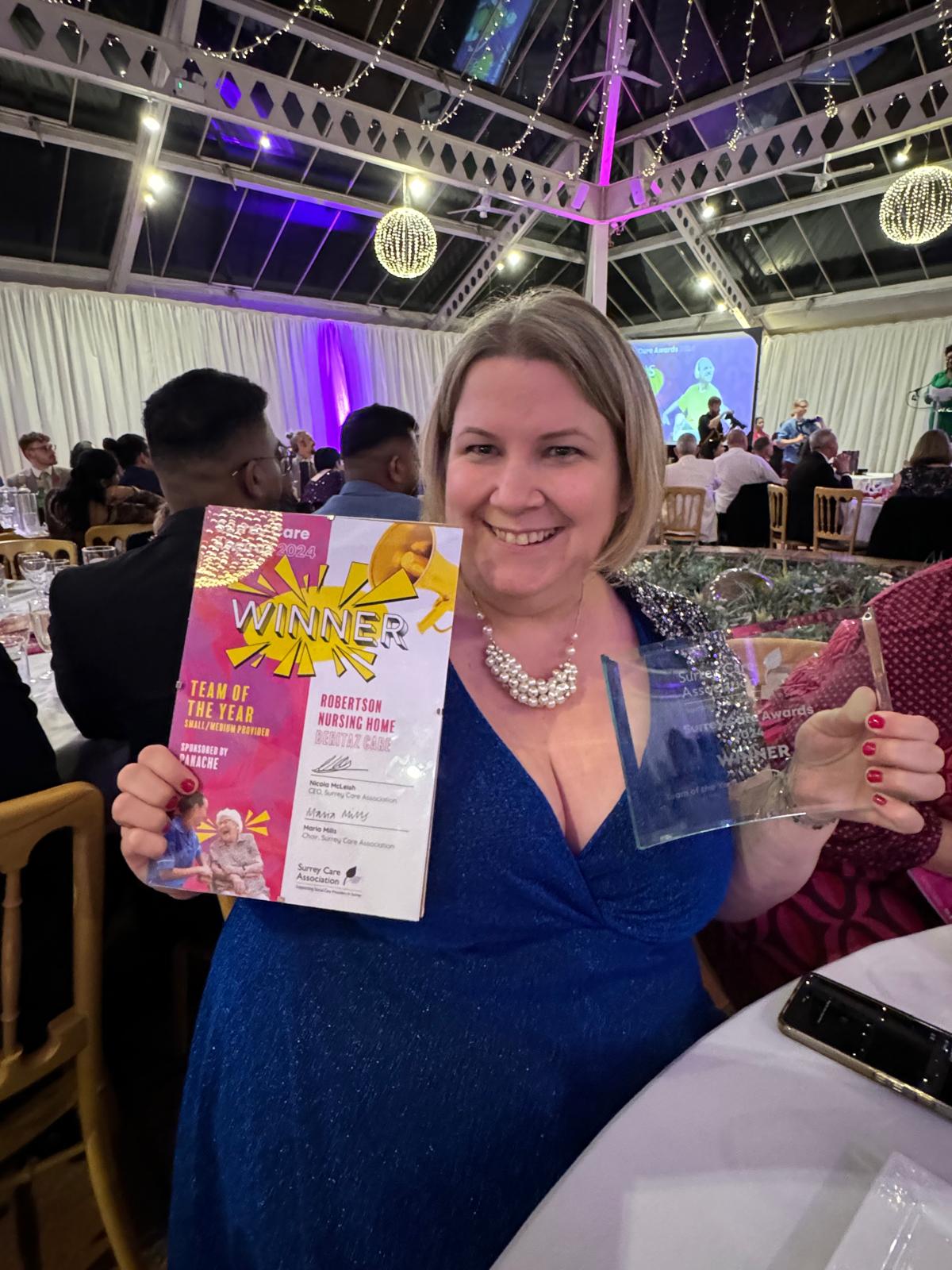A woman holding an award with a huge smile.