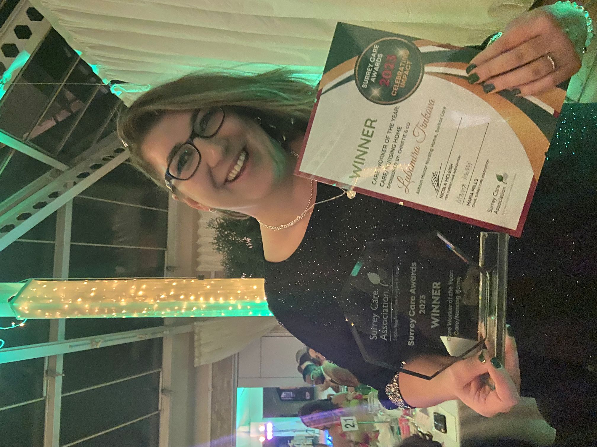 A woman holding an award with a huge smile.