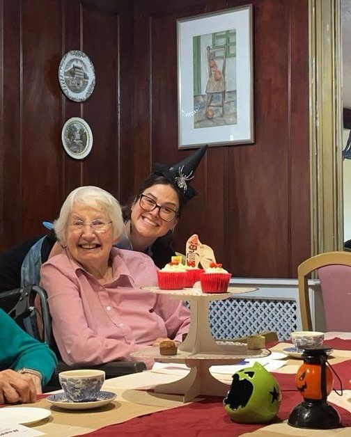 Two women smiling with cupcakes on a table