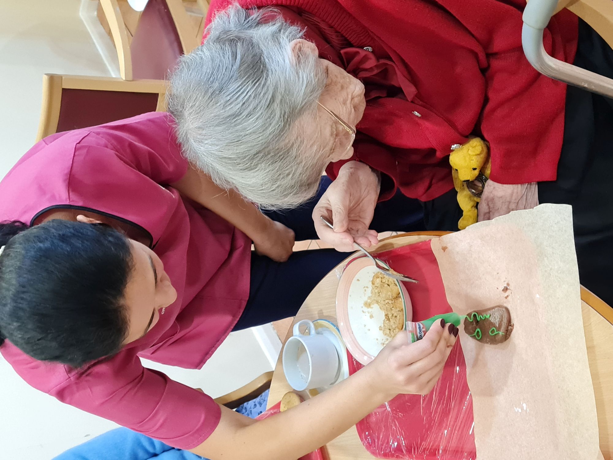 A carer helping a resident decorate a cookie