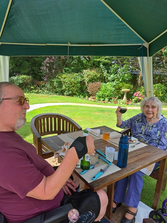 Man and woman eating dinner in the garden under a canopy
