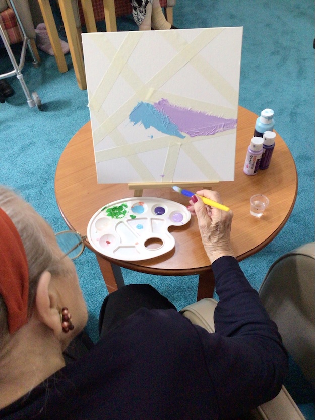 Elderly woman painting on a canvas
