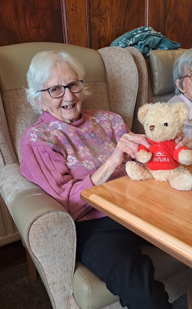 Elderly woman smiling and holding a teddy bear