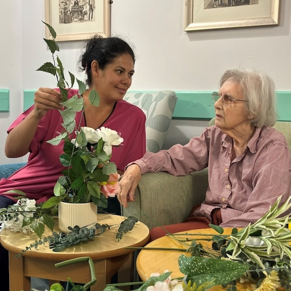 Staff member helping resident with flower arranging activitiy