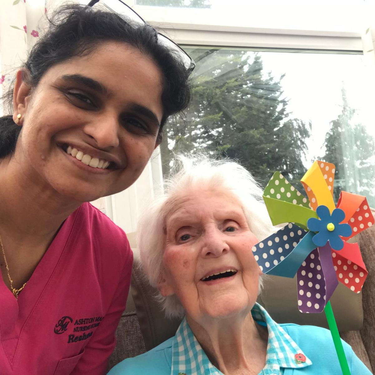 Resident and staff member smiling holding a windmill