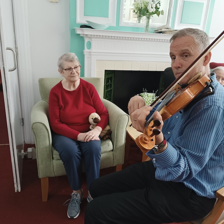 A man playing a violin while sat with an older woman
