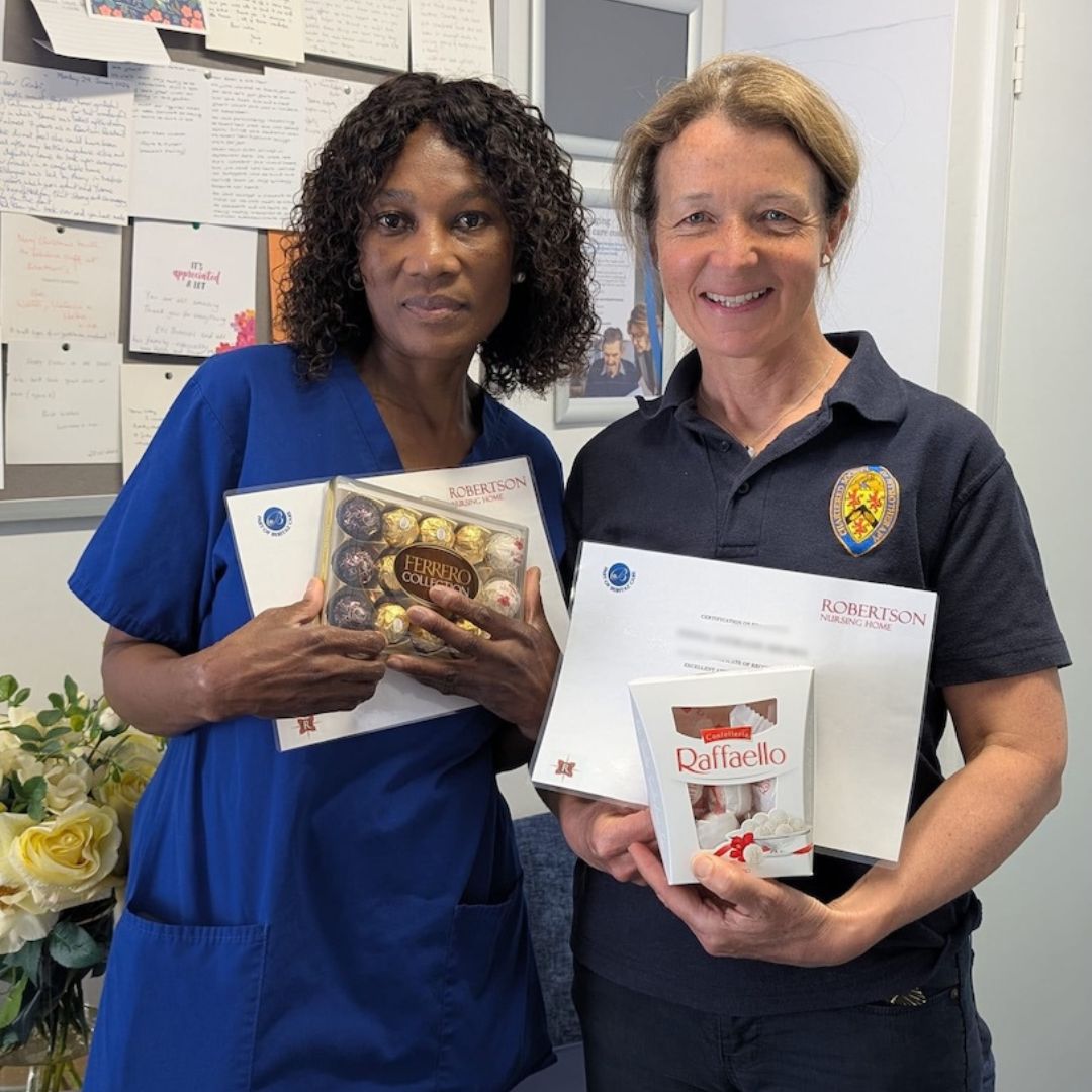 Two staff members holding certificates of achievement