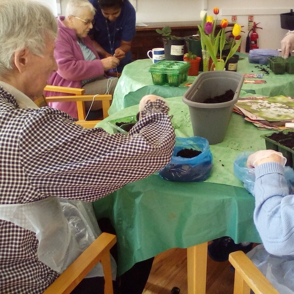 A group of people sat at a table planting seeds