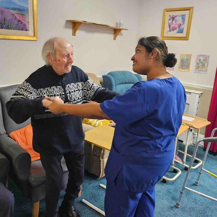 A resident and staff member dancing