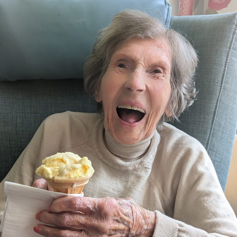 An elderly lady smiling while holding an ice cream