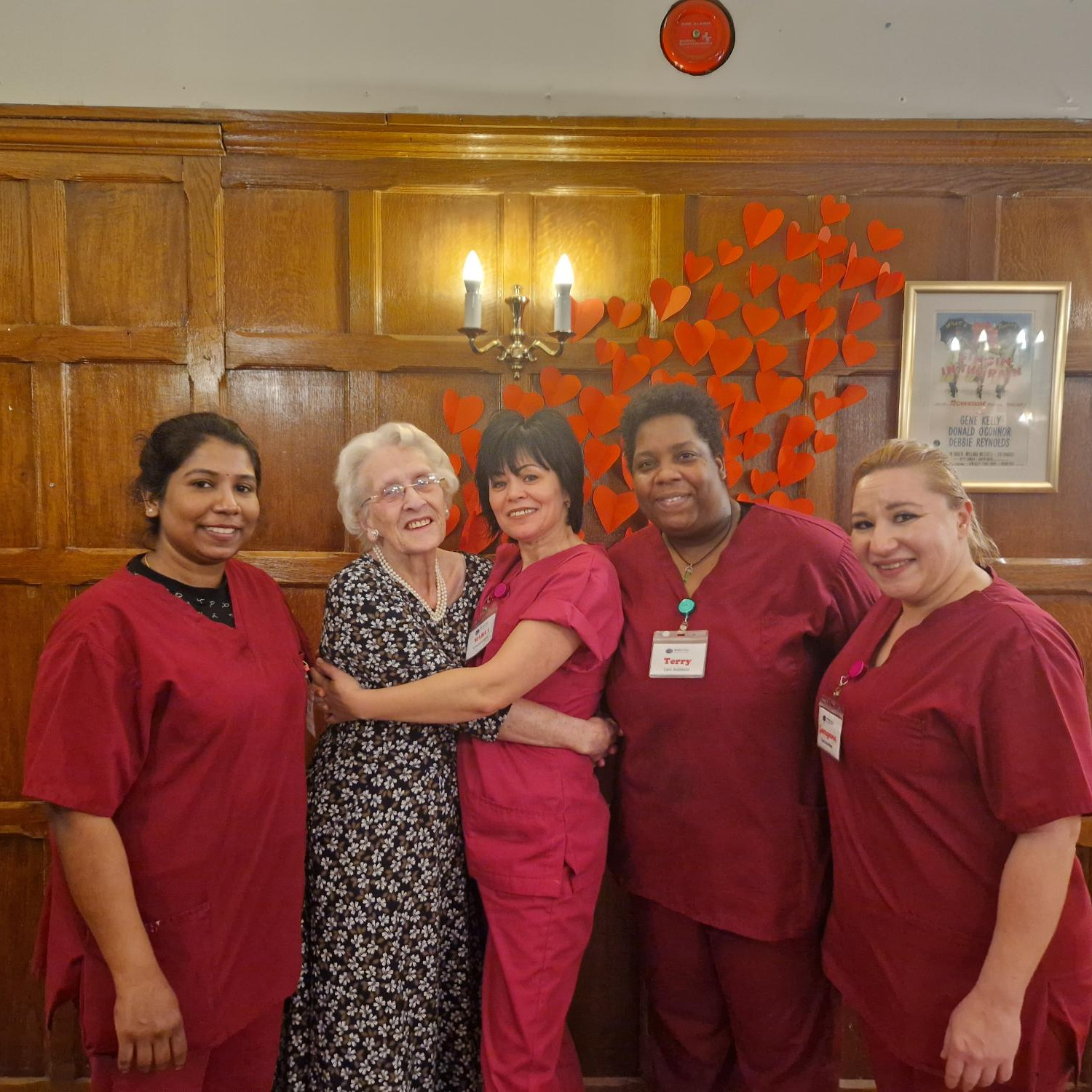 A group of female staff members and a resident, hugging and smiling